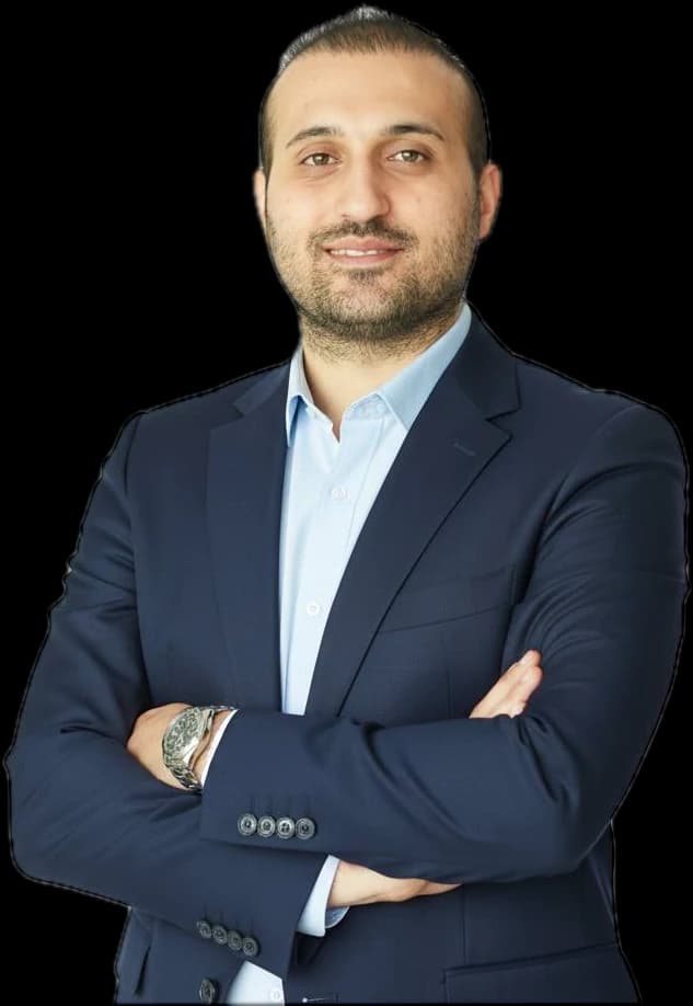 Mo Ghasemi, smiling, arms folded, in a navy suit and light blue shirt